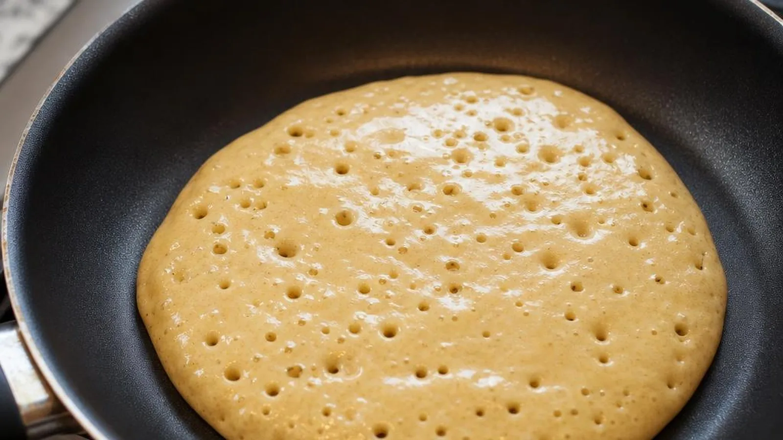 Panqueque cocinándose en sartén con burbujas en la superficie