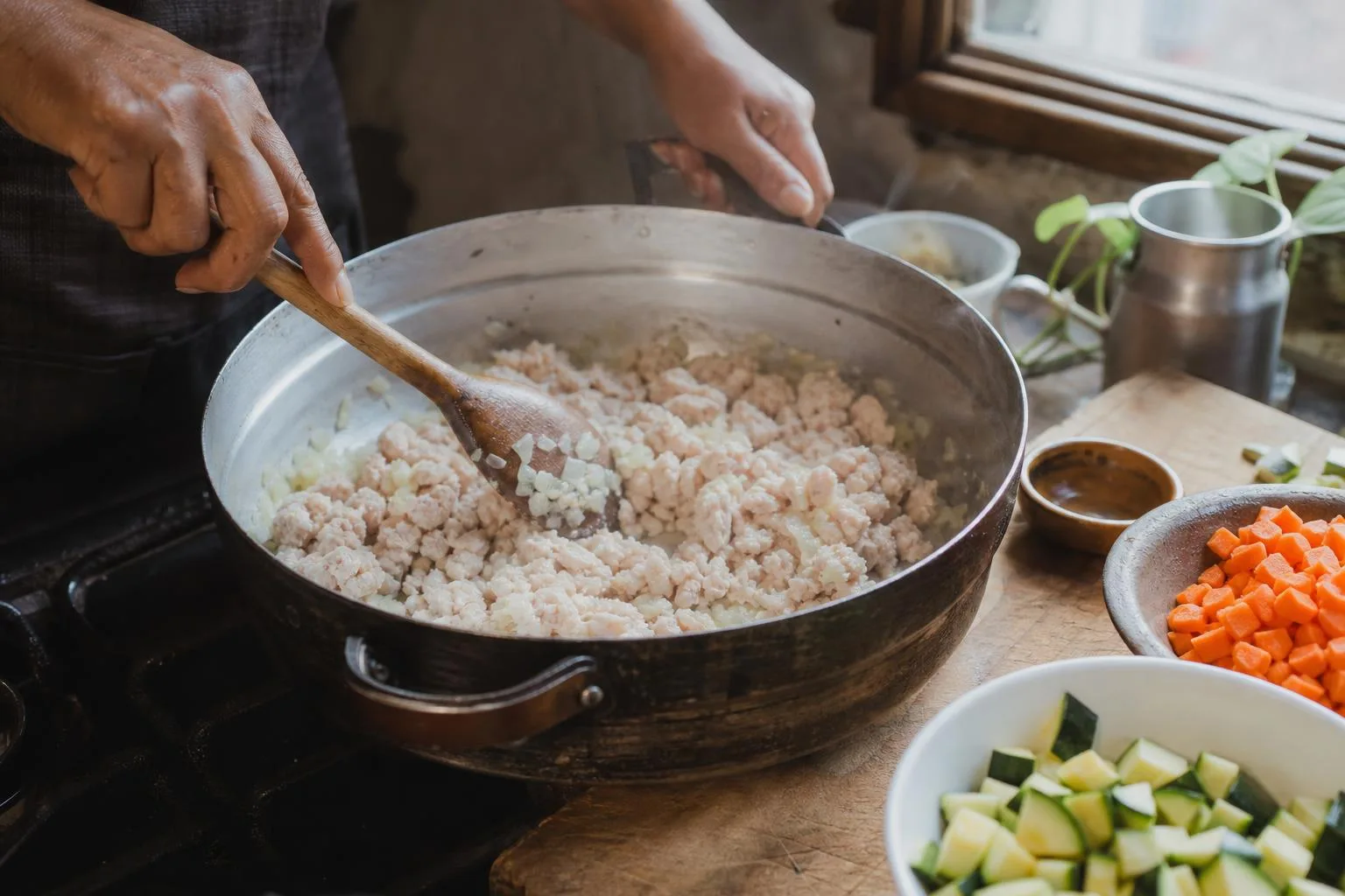 Manos cocinando picadillo blanco de pollo con verduras en sarten casero