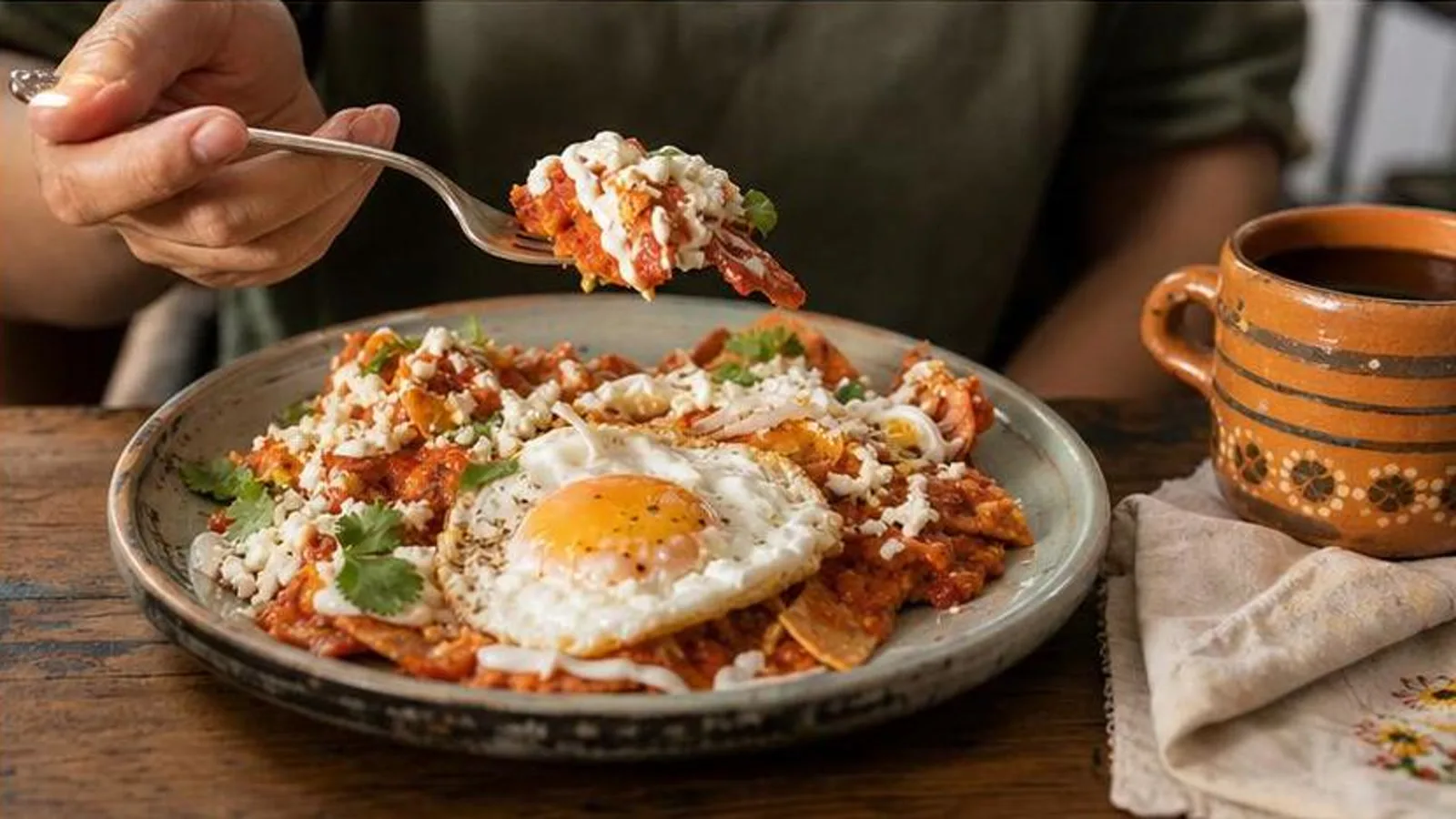 Chilaquiles rojos con huevo servidos en mesa de desayuno casera