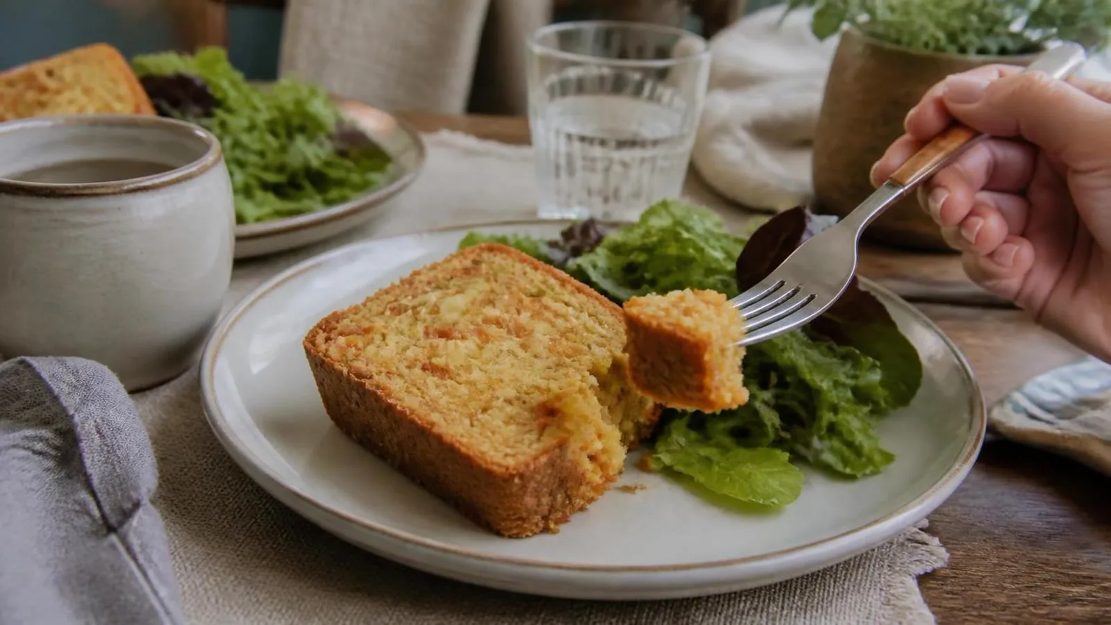 Rebanada de panque salado de zanahoria con queso y avena servida con ensalada en mesa casera