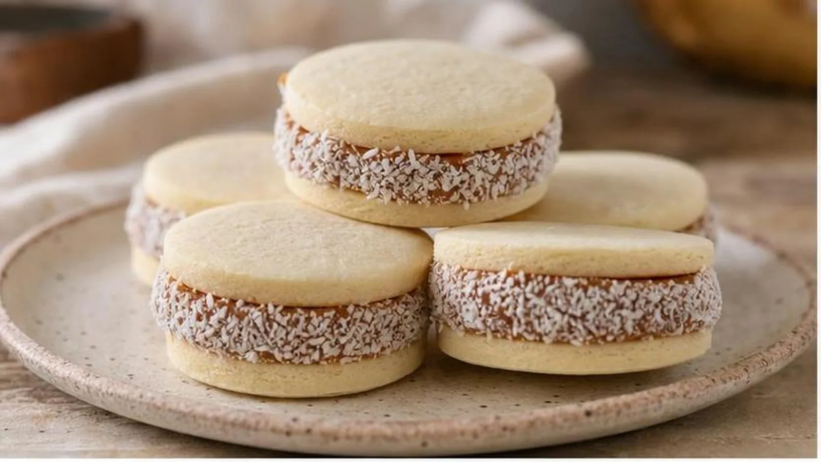 Alfajores de maicena clasicos con dulce de leche y coco rallado servidos en mesa casera