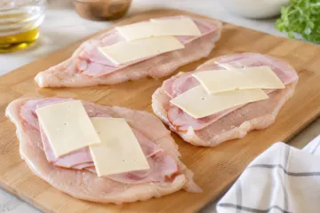 Pechugas de pollo abiertas con jamón y queso listas para enrollar